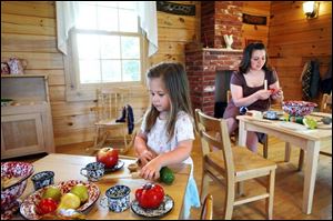 Emilia Braman, 2, and her mother, Autumn, of Battle Creek, Mich., settle into Sauder Village's Little Pioneers Homestead, which includes a cabin and barn with furnishings aimed at the stroller crowd. 
