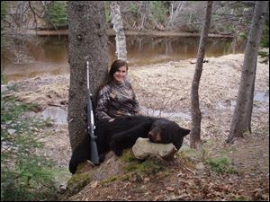 Rachelle Raymer-Gilbert of Sylvania shows off the 240-pound black bear she dropped in the New Brunswick woods. She was one of nine hunters from the Toledo area on the trip.