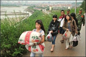 Earthquake survivors carry their belongings to move to higher grounds as the drainage has begun at the swollen Tangjiashan quake lake at Mianyang in southwest China's Sichuan province on Saturday June 7, 2008. 