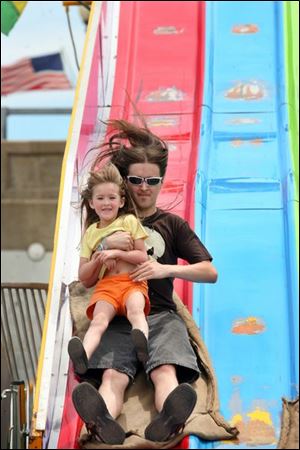 Slug: NBRN carnival19p     Date: 6/15/2008             The Blade/Amy E. Voigt       Location:  Monroe, Michigan CAPTION: Christian Stone, from Monroe, holds his daughter (CQ daughter not sis)  Madison Stone, while riding on a giant slide at the County Chamber of Commerce's River Days Carnival in Monroe on June 15, 2008.