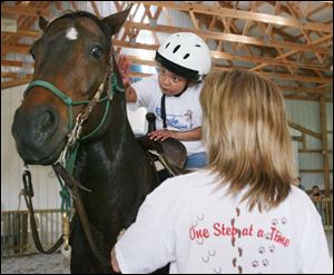 A participant in Serenity Farm's Lucky Riders program pets her steed as Michelle Reiter, a farm board member, helps. The program's intended to boost balance, posture, and socialization.