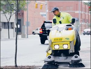 Vincent Davis, a Downtown Toledo Business Improvement District employee, sweeps a section of Huron Street as part of the agency s goal to keep downtown streets clean and safe.
