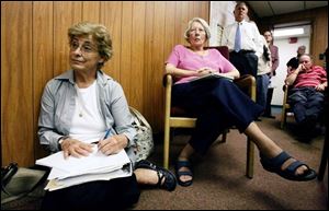 Jackie Fletcher, on floor, and Mary Lewis, supporters of saving the 1884 courthouse from demolition,
listen as the Tiffin Architectural Board of Review meets with commissioners.