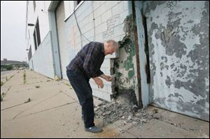 Jim Cherry of Harper Woods, Mich., picks up a piece of the crumbling wall at Tiger Stadium, which is being readied for demolition.