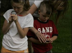 NBRW compass03p  06/25/2008  Blade Photo/Lori King  from left: Brooke Robbins, 8, and Ceal Savidge, 6, with his mom, Jennifer Savidge, learn how to use a compass during the compass course challenge at Secor Metropark in Sylvania,  Ohio.
