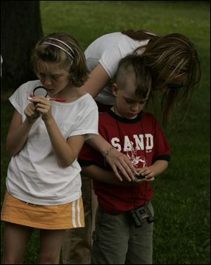 NBRW compass03p  06/25/2008  Blade Photo/Lori King  from left: Brooke Robbins, 8, and Ceal Savidge, 6, with his mom, Jennifer Savidge, learn how to use a compass during the compass course challenge at Secor Metropark in Sylvania,  Ohio.