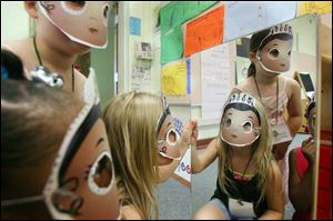 Elizabeth Martin, center, and her friends Olivia Ickes, standing at left, and Ashia Owens examine the masks that they made on the last day of a weeklong program at the East Toledo Family Center to help children become better readers. The program was sponsored by the center and WGTE TV 30. The lessons are incorporated with the PBS program Super Why!, a literacy-oriented program for preschoolers. 