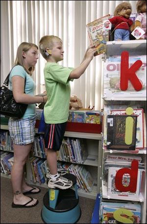 Six-year-old Tyler Kelly selects a book during the summer Accelerated Reading Program at Dorr Elementary School. 