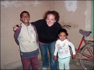 Rebecca Gehring of Toledo, poses with her little 'siblings' from her Moroccan host family, Mohammed, left, and Eham, right, in a village where she served as part of the Peace Corps.