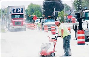 Tod Boose of Smith Paving Inc. of Norwalk, Ohio, cuts new concrete on U.S. 20 on Woodville's west side. On Monday, traffic on U.S. 20 will be shifted over to the 
newly built north half of the roadway within the 
village limits
so work may proceed on the existing roadway.