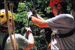 A guide, left, shows writer Mike Kelly how to maneuver on the zipline.
