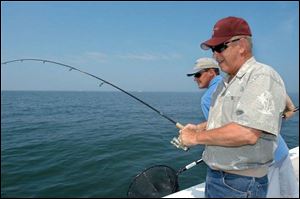 Gov. Ted Strickland battles a fi sh on Lake Erie while State Rep. Chris Redfern (D., Catawba Island) waits with a landing net, just in case.