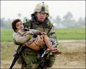 In a picture widely published at the start of the Iraq war, Pfc. Joseph Dyer, 26, was photographed carrying an Iraqi boy injured during battle to a makeshift military hospital.