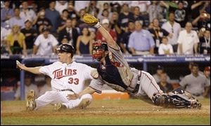 Minnesota Twins' Justin Morneau (33), of the American League team, and Atlanta Braves' Brian McCann, of the National League team, react after Morneau scored the winning run on a sacrifice fly by Texas Rangers' Michael Young in the 15th inning in the Major League Baseball All-Star Game at Yankee Stadium in New York on Wednesday.