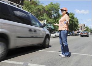 Police Officer Grace Delgado throws up her arms as a van speeds past her in a crosswalk, violating a law that requires drivers to stop when a pedestrian takes a single step off the curb.