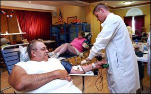 David Ross of Oregon is monitored by Red Cross employee Sean Burgoon while giving blood yesterday at Little Sisters of the Poor. Blood shortages crop up every summer.
