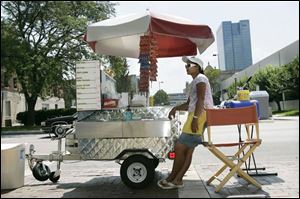 Shaded by her cart's umbrella, lunch vendor Nikki Burado awaits customers outside the Safety Building.