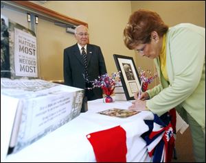 Bill Krouse and Nelma Burnard sign Bibles at Shelton Park Church of God. The Bibles will be given to U.S. troops.
