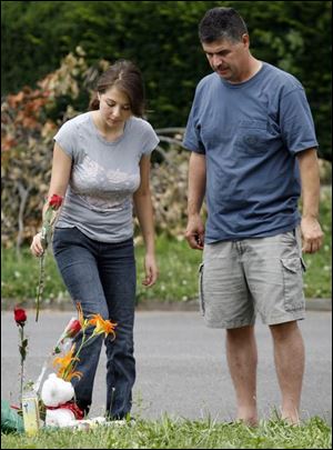 Bianca Salinas, 14, with her father, John, places a rose on an informal memorial to her friend Kenneth Kimble near the corner of Idaho and White streets in East Toledo.