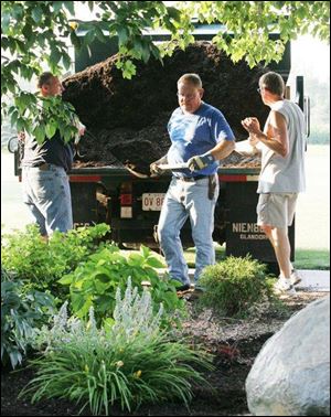Paul Rieman, Dan Bockrath, and Joe Kleman, from left, shovel mulch onto a garden area near the miniature golf course, which is among the park s many features built by citizens.