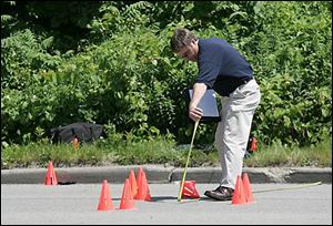 Det. Terry Cousino collects evidence at a police shooting on Detroit Ave. near Crawford in Toledo on Wednesday.
