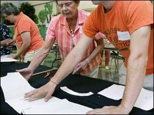 NBRW uniforms24p  07/17/ 2008 The Blade/Dave Zapotosky Caption: Donna Tallent of Westgate Chapel in Toledo, left, helps David McChesney of Gesu Church in Toledo, right, layout a paper pattern on a piece of fabric so he can cutout pieces of a uniform jumper at Sylvania United Church of Christ in Sylvania, Ohio, Thursday, July 17, 2008.  The skirt and jumper kits will be sewn together by volunteers at a late date and distributed to needy Toledo Public School students.  Summary: Volunteers will be packaging kits of school uniforms for low income kids from 9 a.m. to noon July 17 and 24. The uniforms are distributed by Project Dignity.