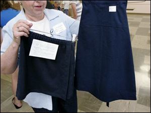 NBRW uniforms24p  07/17/ 2008 The Blade/Dave Zapotosky Caption: Ellen Bowers, coordinator of the uniform project at Sylvania United Church of Christ in Sylvania, Ohio, displays samples of the uniform skirts and jumpers volunteers from various churches are making, Thursday, July 17, 2008.  Volunteers were cutting out the pieces of the skirt and jumper kits, which will be sewn together by volunteers at a late date and distributed to needy Toledo Public School students.  Summary: Volunteers will be packaging kits of school uniforms for low income kids from 9 a.m. to noon July 17 and 24. The uniforms are distributed by Project Dignity.