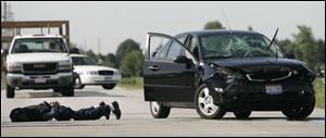 The suspect of a bank robbery lies in the road near Haskins, Ohio. He was caught within 30 minutes of a 911 call. (SENTINEL-TRIBUNE)
<br>
<img src=http://www.toledoblade.com/graphics/icons/audio.gif> <font color=red><b> LISTEN:</b></font> <a href=