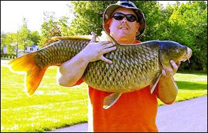 Rich Cady of Newark, Ohio, used a bow and arrow to subdue this record 47.65-pound carp in Sandusky Bay, near Lake Erie. 