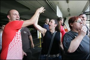 Oliver Furniss, left, and Marina Scaffidi, center, passengers on board the Qantas Airways flight QF-030, exchange high-fives after emerging from the passenger plane following an emergency landing at the Ninoy Aquino International Airport on Friday.