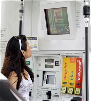 A motorist in Miami turns her attention to the TV screen as she fills her vehicle.