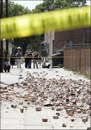 People stand in an alleyway behind police tape near where bricks fell from an unoccupied building during an earthquake Tuesday in Pomona, Calf., near Los Angeles. 