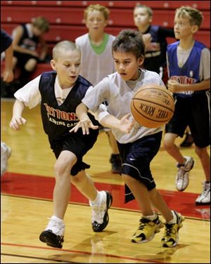 Drew Melick, right, 10, of Sylvania dribbles around Ian Brolley, 10, of Erlanger, Ky., during the Detroit Pistons basketball camp at Owens Community College in Perrysburg Township.
