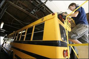 Matt Smith installs a digital camera system in a Monroe school bus. The system records the view on the inside of the bus as well as the bus speed and activation of warning lights, brake lights, and stop sign arms at any time during a bus route. 
