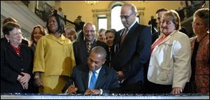 Gov. Deval Patrick, center, surrounded by legislators and supporters, including State Sen. Dianne Wilkerson, third from left, and House Speaker Salvatore DiMasi, third from right, signs a bill at the Statehouse in Boston on Thursday repealing the 1913 law that blocked out-of-state gay couples from marrying in Massachusetts. 