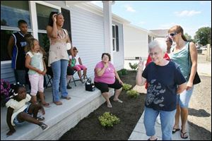 Michelle Kajderowicz, standing on the porch of her new Habitat for Humanity home, greets Darla Figas, on the sidewalk in front, and Deb Schmenk, strolling behind her yesterday.