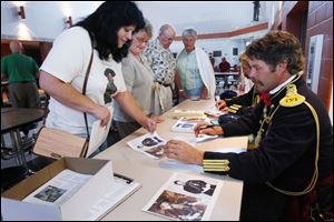Paul Houser, portraying Capt. Tom Custer, and Steve Alexander, as Lt. Col. George Custer, sign autographs for, from left, Shawna Mazur of Monroe, Edie Olds of Bowling Green, and Bill Heiman of Tontogany and his wife, Barbara.