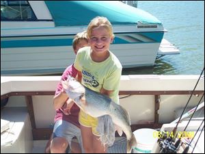 Andrea Cromley, 9, of Bowling Green, with a little help from her brother, Mitch, shows off a 29-inch walleye she landed.