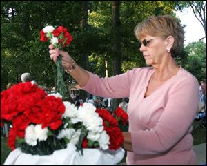Pam Rettig of Findlay gathers flowers to give out to people to save or throw into the adjacent Blanchard River as part of the one-year commemoration of the August, 2007, flood.