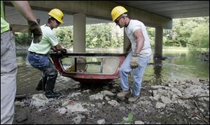 Findlay residents Brian Bibler, left, and Eric Stroub work for the National Emergency Grant Project clearing debris from the Blanchard River in Findlay. 

