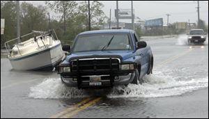 Cars drive past boats displaced by flooding caused by Hurricane Ike, Saturday, Sept. 13, 2008, in Bay View, Texas. 