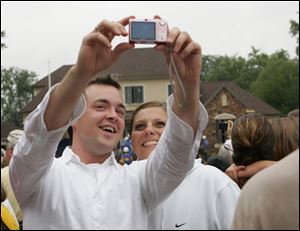 Spectators Christian Smith and Abby Baldwin, both of Toledo, take a self-portrait on the site of the extreme home makeover for the frisch family on Edgedale Circle.