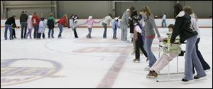 Jamie Frazee, right, in skating chair, is helped around the ice by volunteers during rehearsal for Gliding Stars Adaptive Ice Skating at the University of Findlay's Clauss Ice Arena.