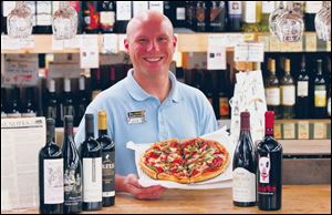 Nick Kubiak of The Andersons holds a pizza that can be enjoyed with  fruit forward  red wines.