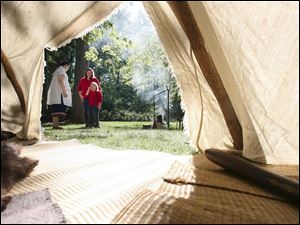 Slug: NBRE swamp09p                             Date: 10/05/2008             The Blade/Amy E. Voigt                     Location: Oregon, Ohio  CAPTION:  Angela Metcalf, left, from Toledo, talks to visitors Sirena Roberts, right, and her mother Rose Roberts, center, from Northwood, while she tends to a campsite in historical costume in front of a Native American Wigwam during the Black Swamp Festival at Pearson Park, Packer-Hammersmith Center on October 5, 2008 in Oregon. The free event included crafts, artisan demonstrations and entertainment.