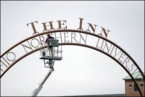 A worker puts the finishing touches on the sign for the college's new 75-room hotel.