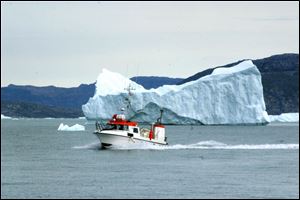 A fishing vessel passes in front of an iceberg along Greenland s northwestern coastline. Icebergs can create killer waves by suddenly flipping.