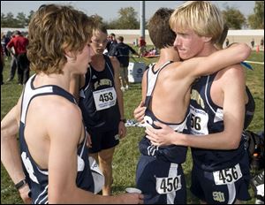 St. John's senior Kevin Yarnell, who finished third overall at 15:42.26, gets a hug from teammate Preston Benjamin as Jacob Van Dootingh, left, and Ben Miller gather after the race.