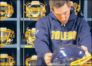 Equipment crew member Josh Billenstein applies a decal to a helmet as he prepares for the next day s practice at UT s Glass Bowl.