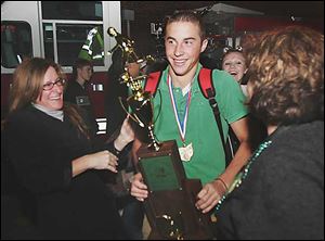 Mary Kuehnle, right, greets her Ottawa Hills soccer playing son, Sam, as Kuehnle family friend Mary Jo Corbey, left, looks on. The trophy young Kuehnle is hefting recognizes Ottawa Hills as the Div. III state high school soccer champion. The Green Bears beat Worthington Christian on Friday 1-0.